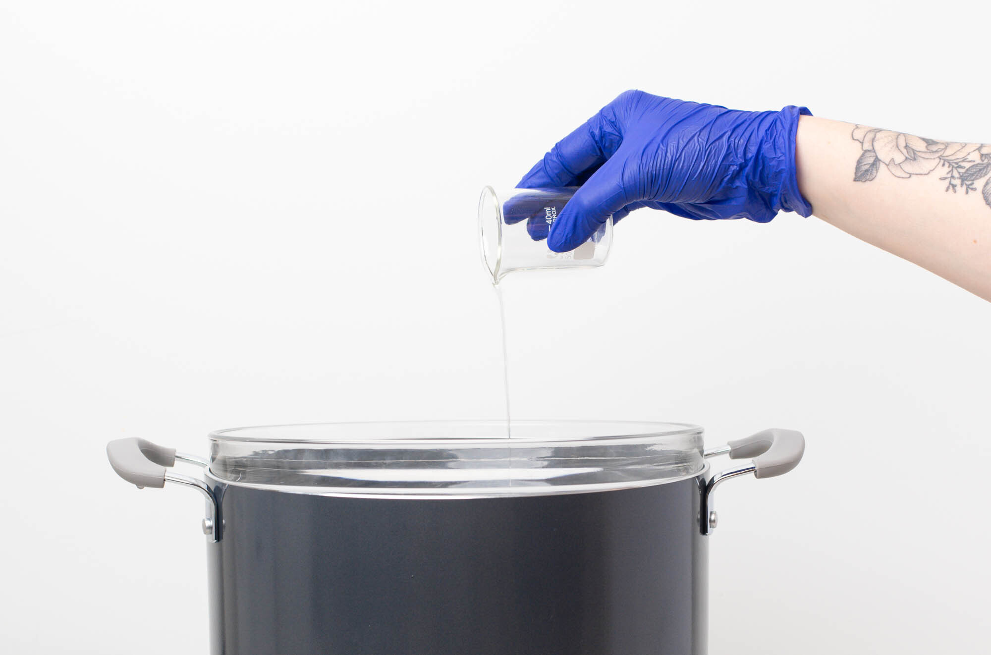 Pouring mixture from pouring pitcher into reed diffuser bottle.